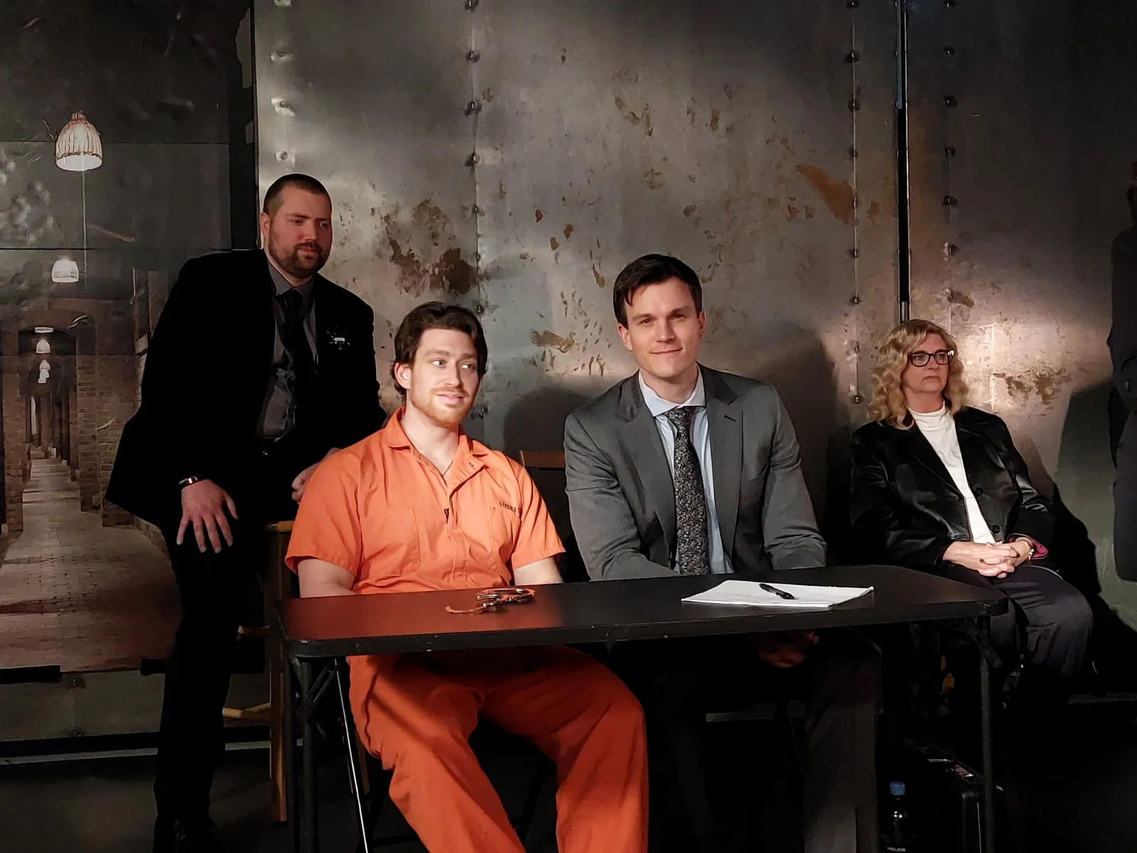 On set — an interrogation scene, the cast seated around the table