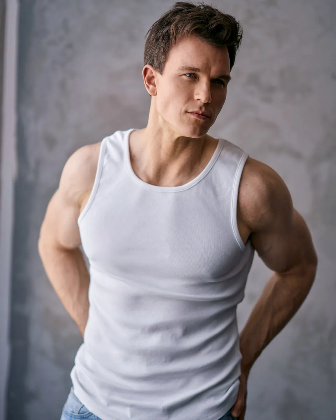 Steven Roderick Jurich in a white tank top against a concrete wall